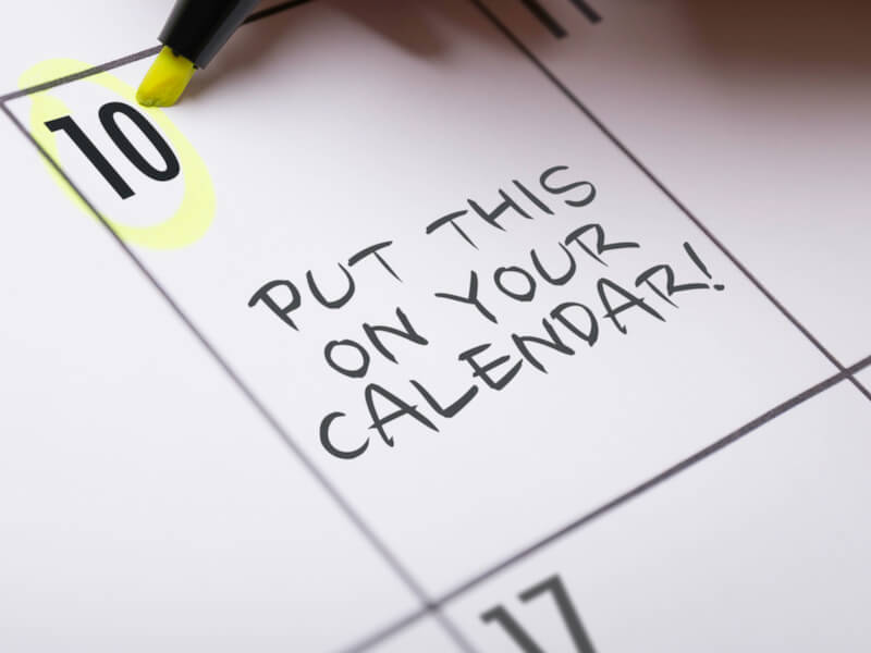 A close-up of a calendar with the 10th highlighted in yellow. The words PUT THIS ON YOUR CALENDAR! are handwritten across the day, with a yellow highlighter marking the date.